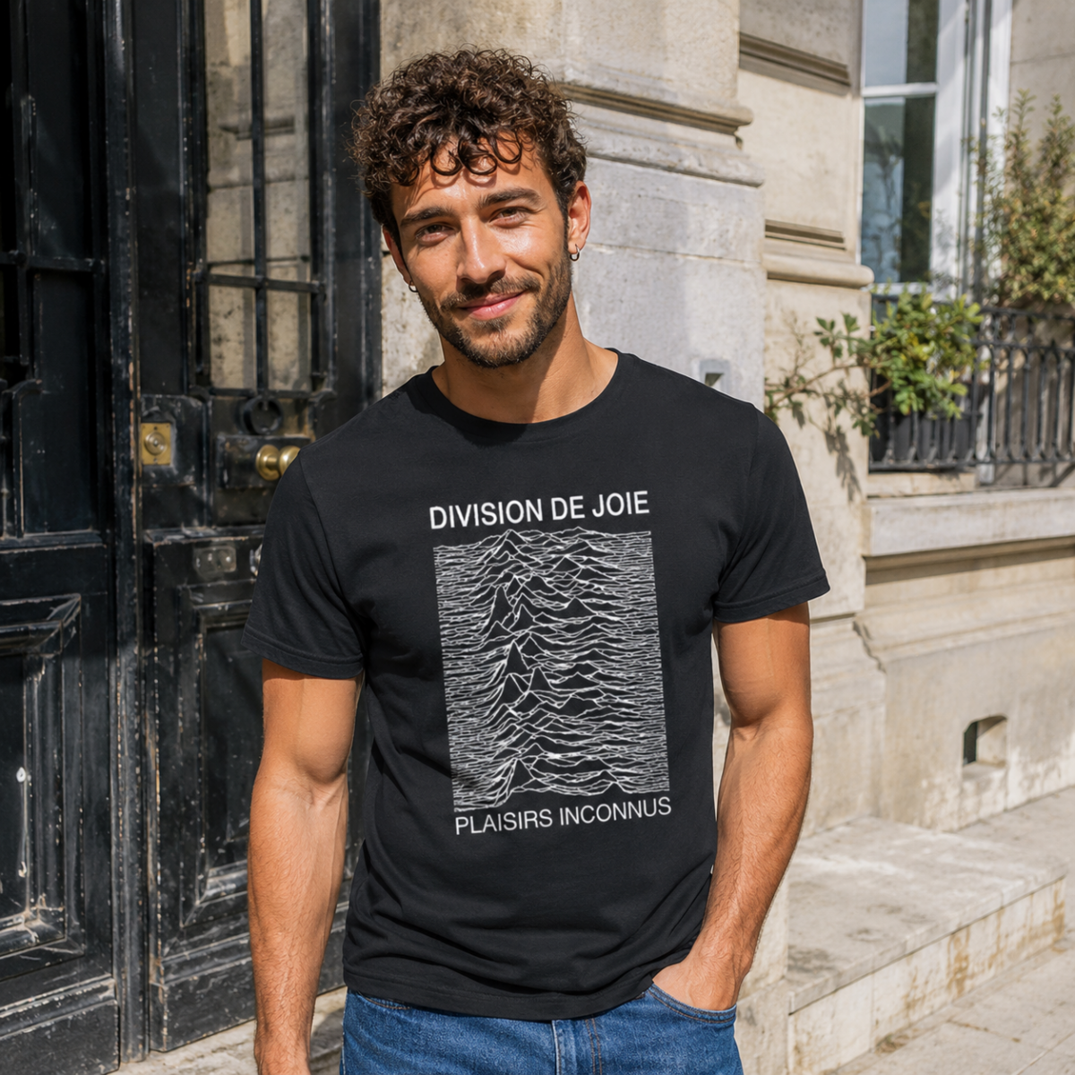 Homme portant le t-shirt noir Division de Joie devant une porte d’immeuble en ville