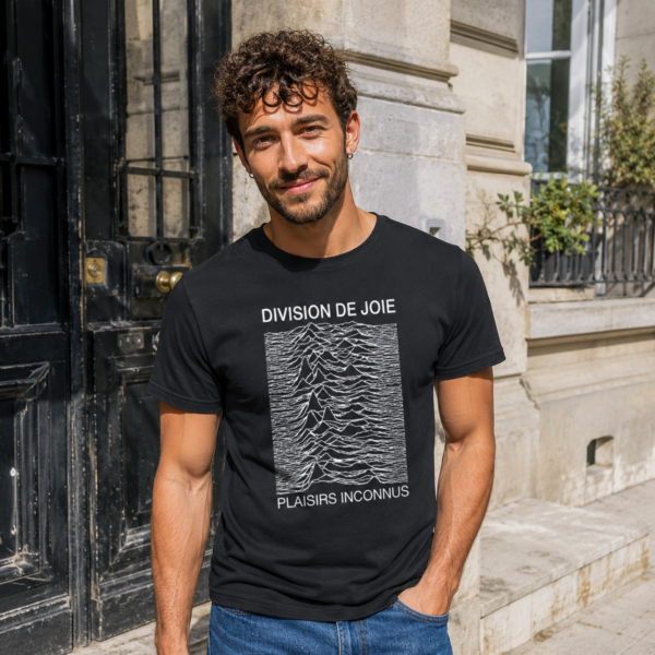 Homme portant le t-shirt noir Division de Joie devant une porte d’immeuble en ville